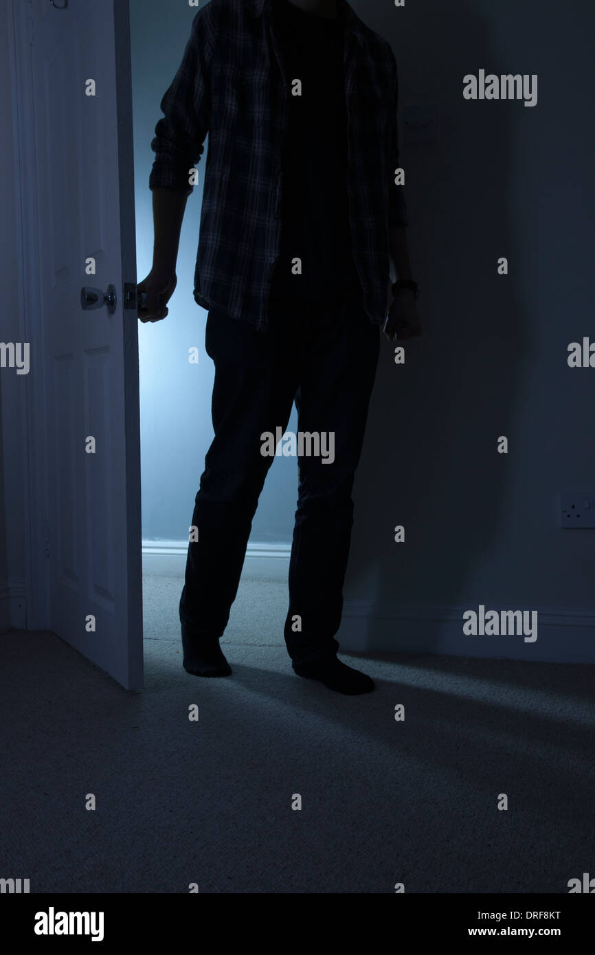 Silhouette di un uomo in piedi al buio in un aperto porta. Foto Stock