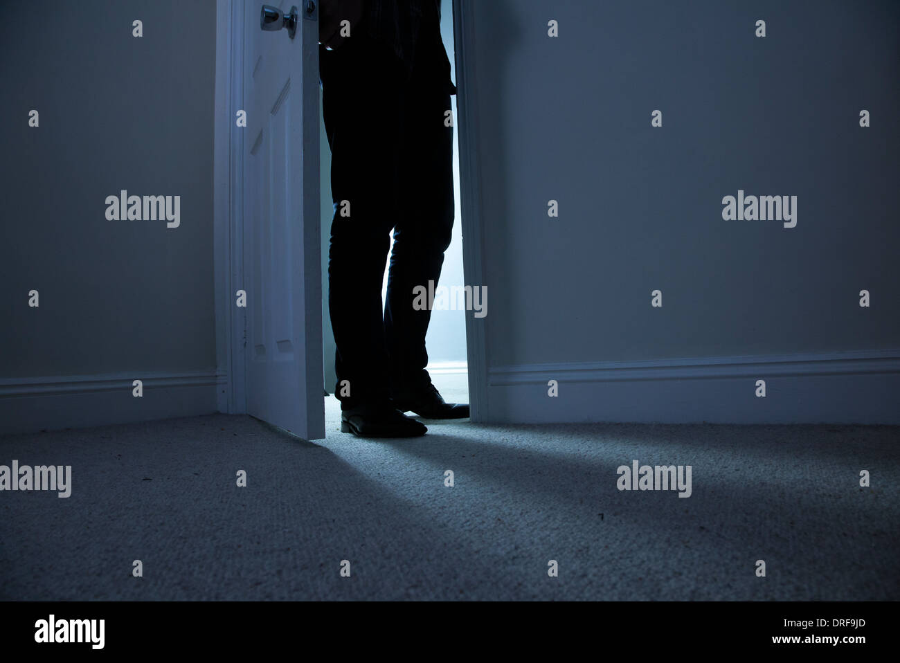 Silhouette di un uomo in piedi al buio in un aperto porta. Foto Stock