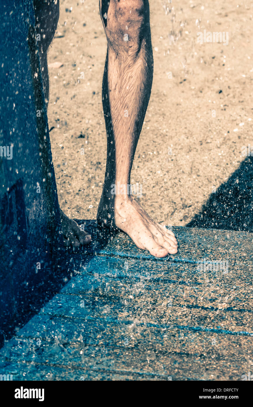 Dettaglio della gamba maschio in doccia spiaggia all'aperto Foto Stock