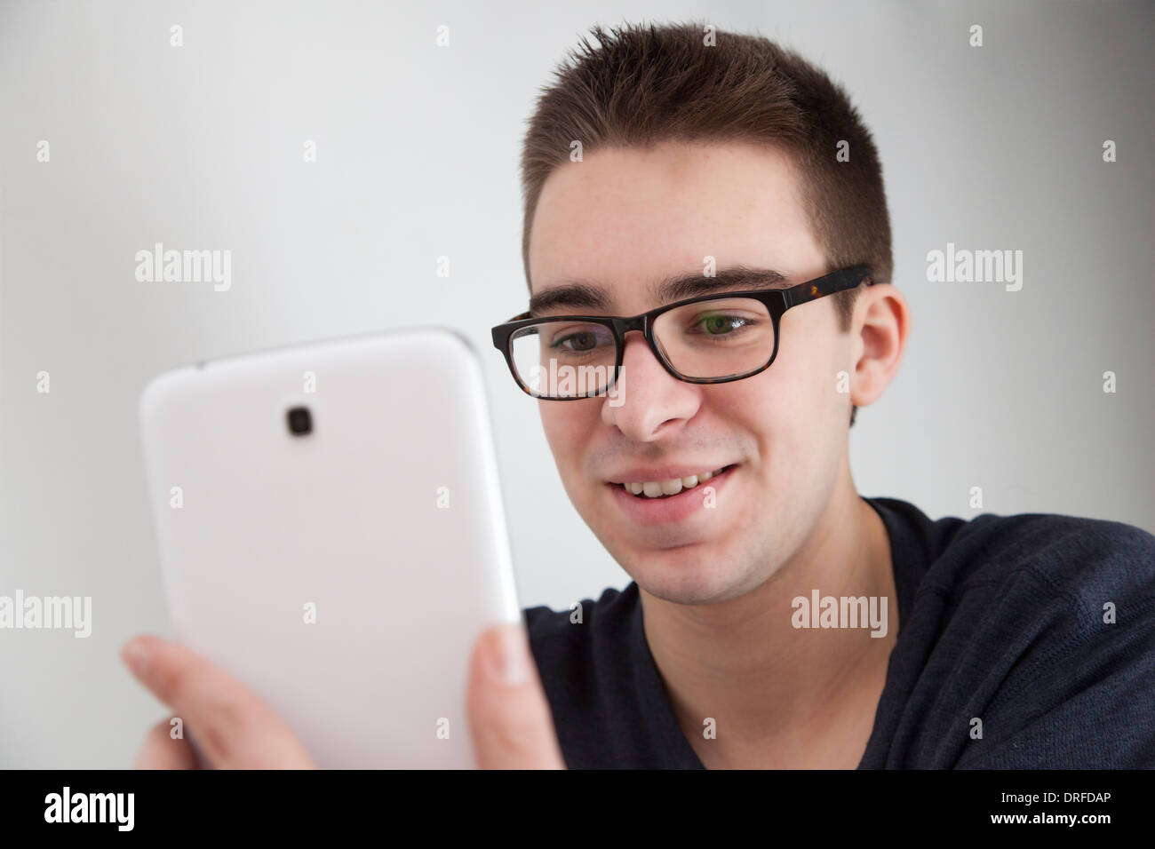 Buona ricerca giovane con gli occhiali, sorridenti mentre si tiene un bianco digitale compressa. Foto Stock