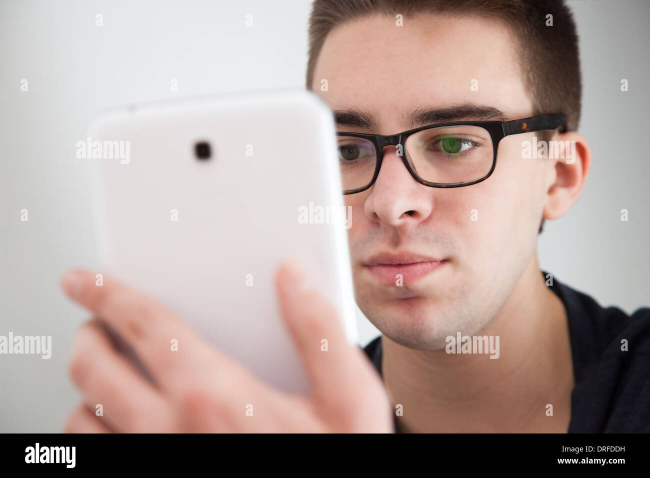 Buona ricerca giovane con gli occhiali, tenendo in mano un bianco digitale compressa. Espressione seria. Foto Stock