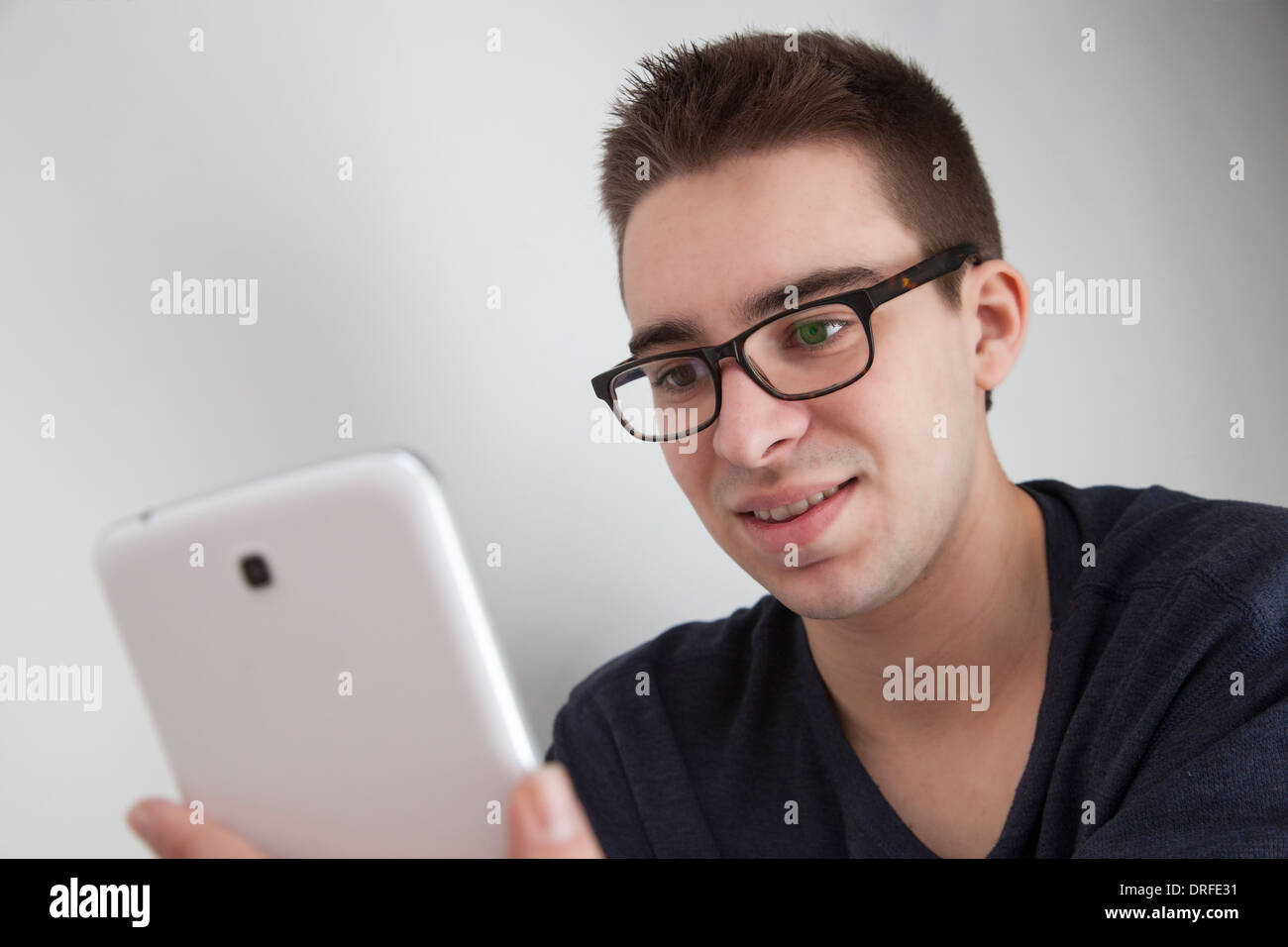 Sorridente buona ricerca giovane con gli occhiali, sorridenti mentre si tiene un bianco digitale compressa. Foto Stock