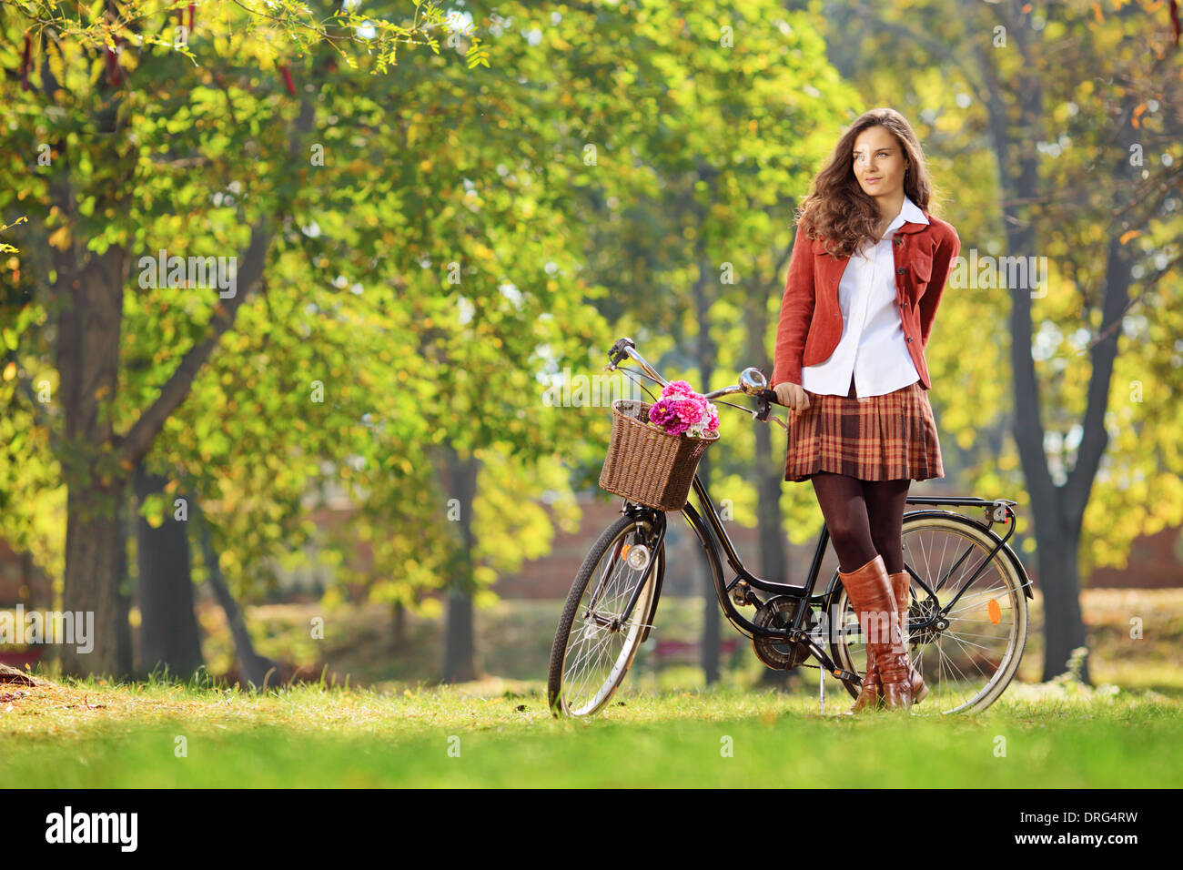 Bella giovane femmina che pongono nel parco con la sua bicicletta Foto Stock