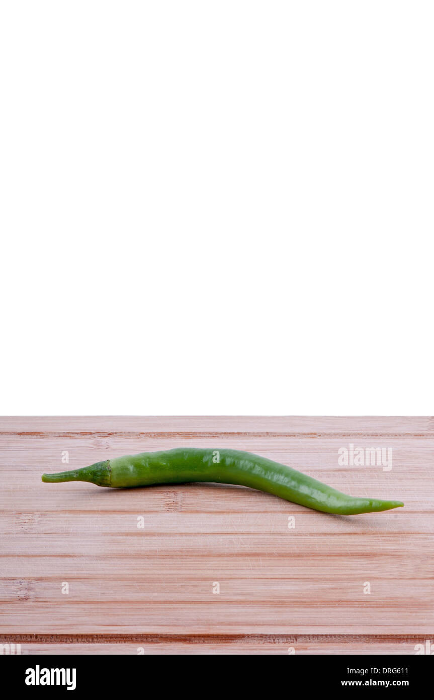 Peperoncini verdi su invecchiato boarrd trinciatura su sfondo bianco verticale. Foto Stock