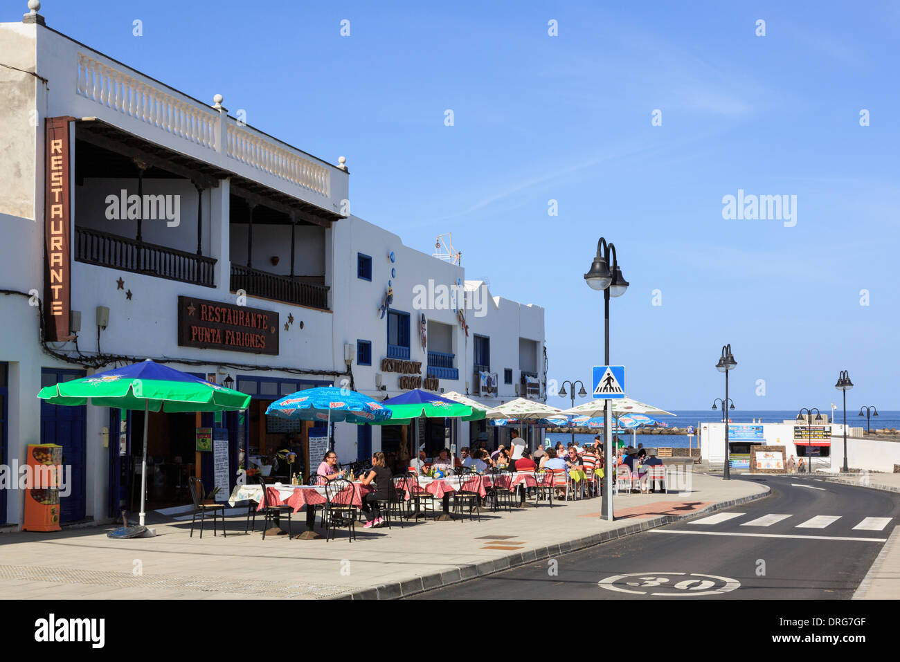Sala da pranzo di persone al di fuori di un cafe' sul marciapiede in maggior parte nord del villaggio resort di Orzola, Lanzarote, Isole Canarie, Spagna Foto Stock