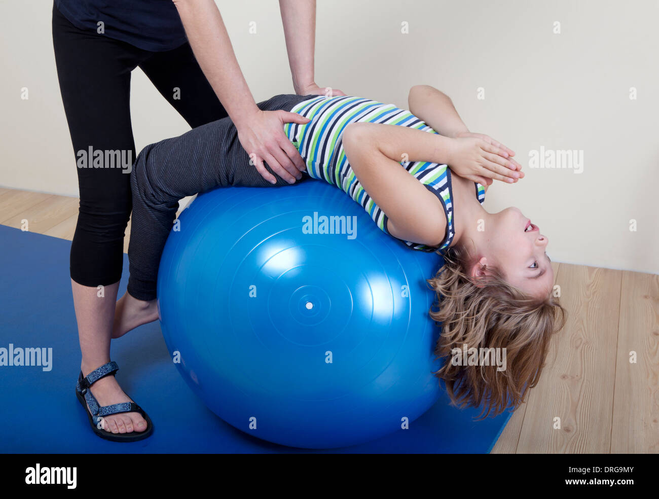 I bambini fare ginnastica su di una sfera, un terapista fisico mostra gli esercizi per la schiena Foto Stock