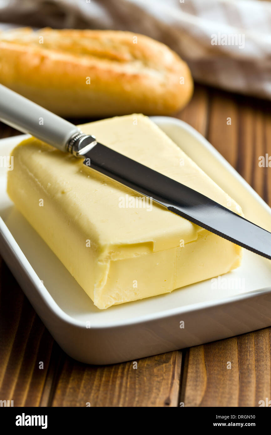 Cubo di burro con il coltello sul tavolo di legno Foto Stock