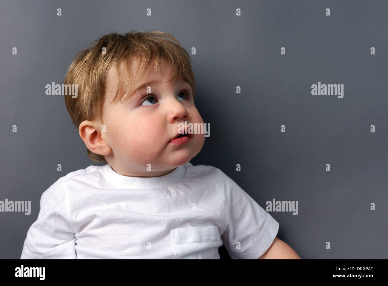 Carino piccola bionda toddler boy guardando in alto, sicuri Foto Stock