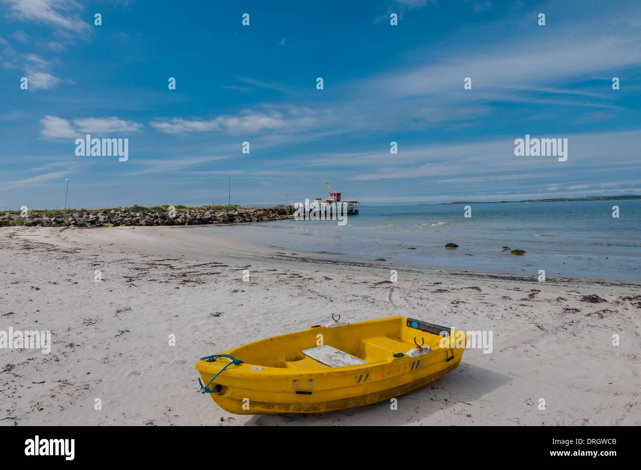 Piccola barca gialla sulla spiaggia Tayinloan penisola di Kintyre con Caledonian MacBrayne traghetto per auto 'Loch Ranza' in Scozia in background Foto Stock