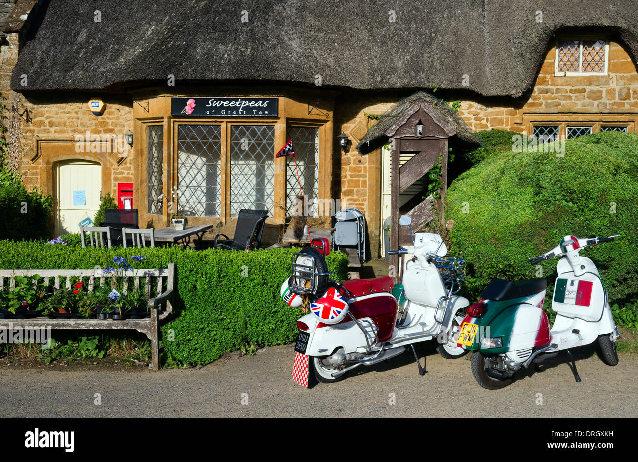 Due vintage lambretta parcheggiata fuori con tetto di paglia costruita in pietra arenaria Cotswold cottage Foto Stock