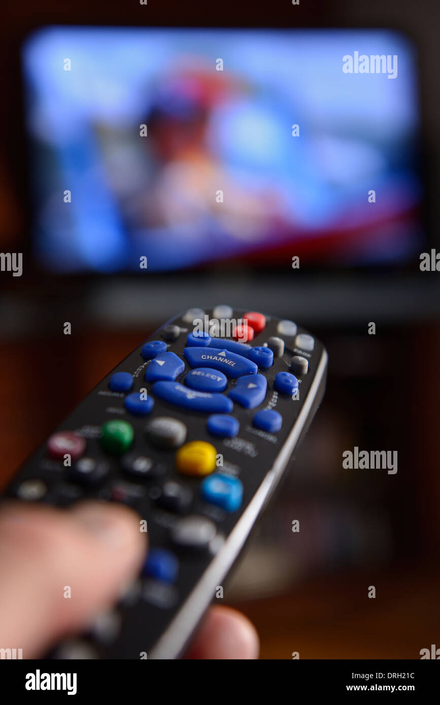 Persona puntando il telecomando universale verso uno schermo televisivo per modificare il programma di sistema di intrattenimento Foto Stock