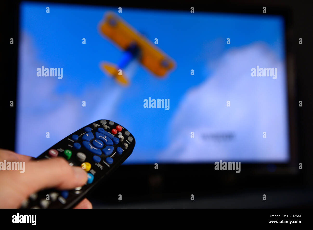 Un uomo indica un telecomando universale verso uno schermo televisivo per modificare il programma sul sistema di intrattenimento Foto Stock