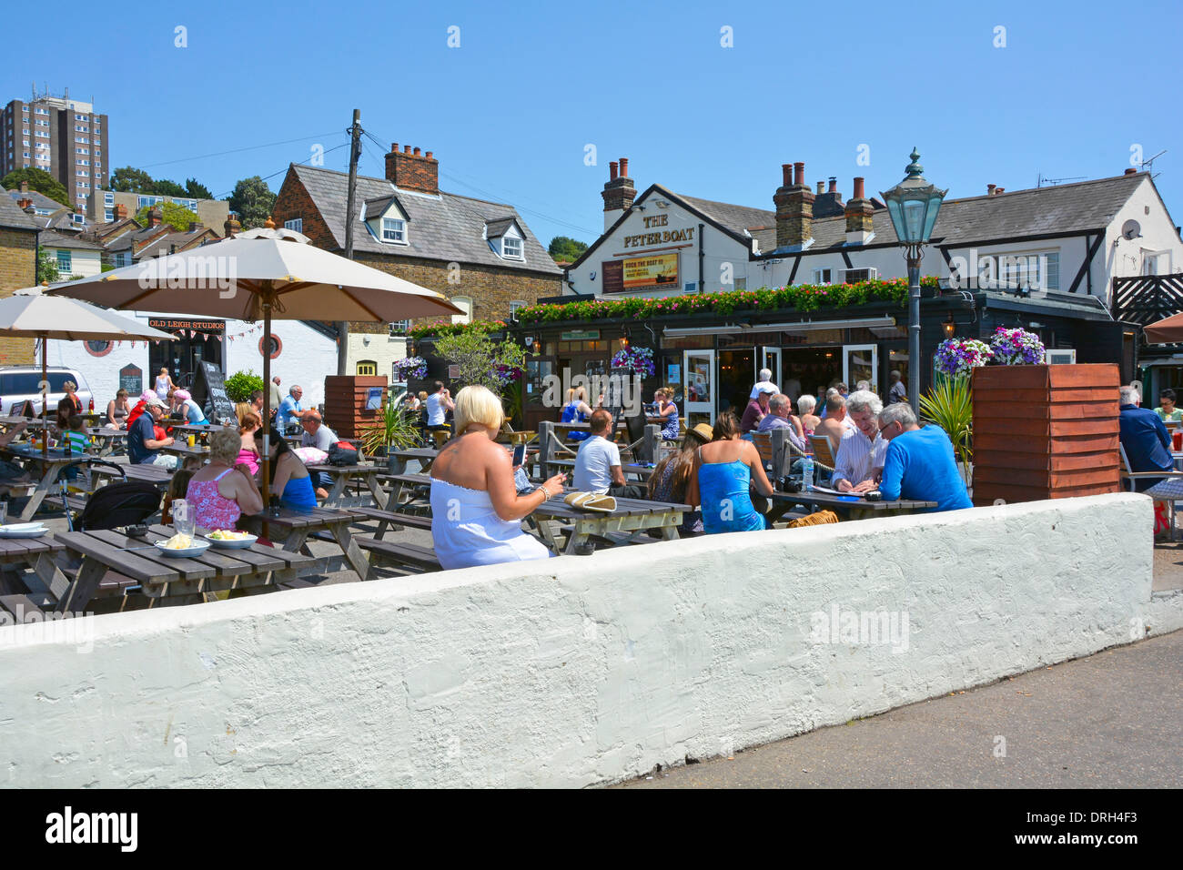 Persone su tavoli all'aperto accanto alla promenade a Leigh on Sea in una calda giornata estiva Foto Stock