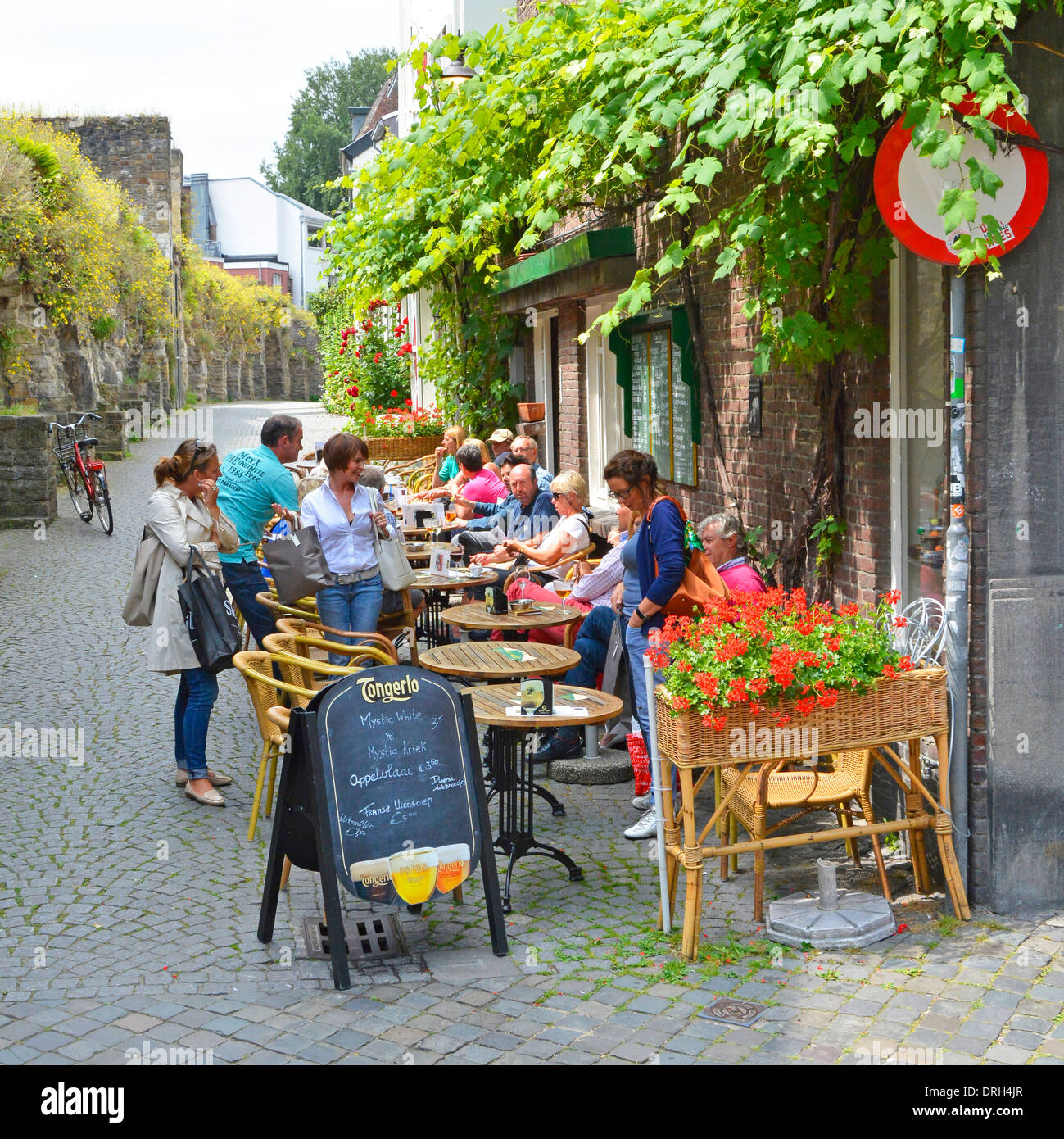 I turisti e gli abitanti del luogo del caffè di Maastricht si godono una bibita rinfrescante seduti all'aperto in una graziosa strada laterale olandese in estate Limburgo Paesi Bassi e UE Foto Stock