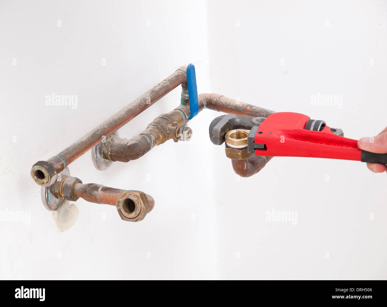 Le mani la riparazione dei tubi idraulici di un boiler elettrico con una chiave stilson Foto Stock