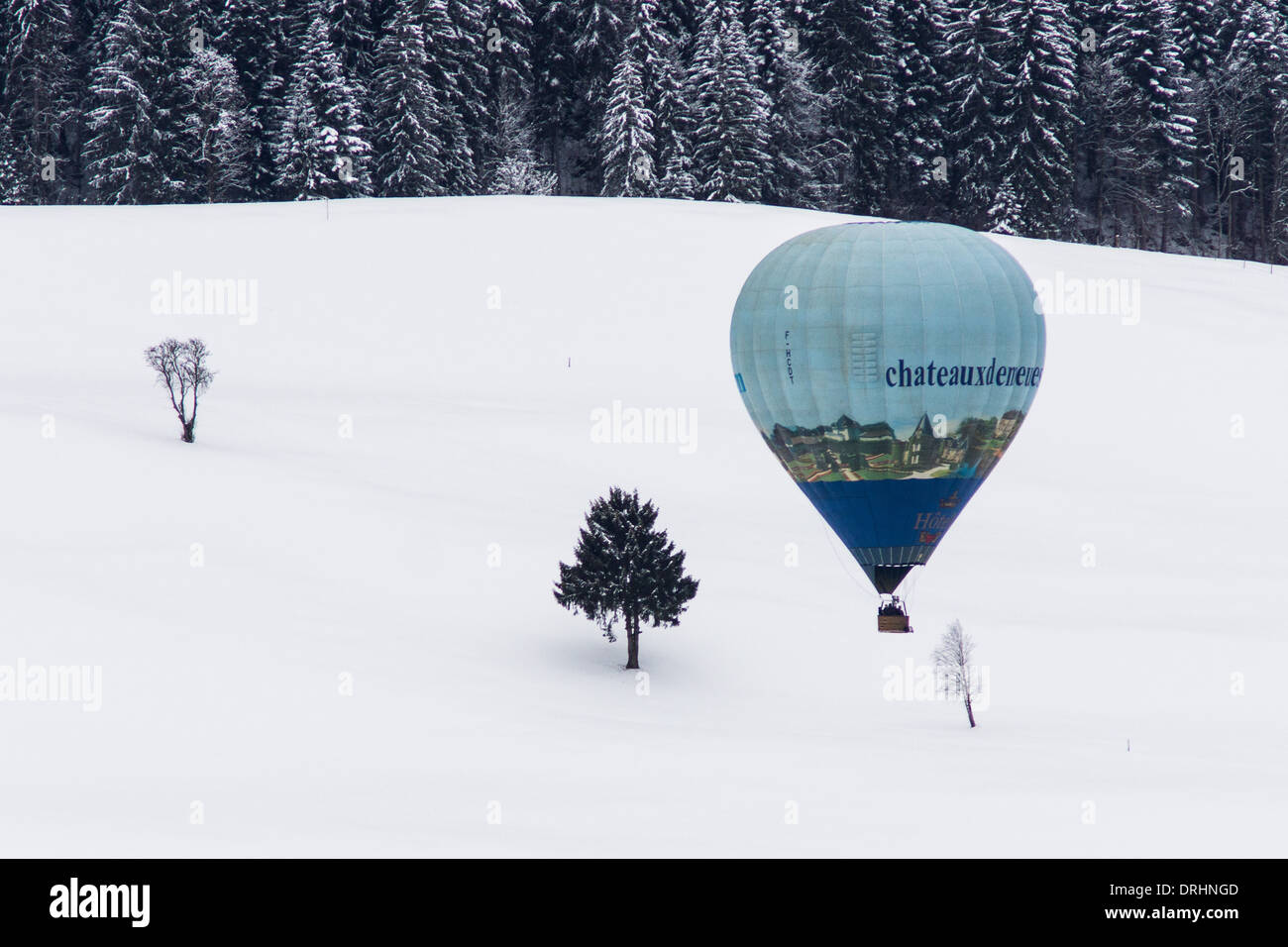 Pilota francese Gilles De Crick volare sopra gli alberi solitari. Chateau d'Oex, Svizzera Foto Stock