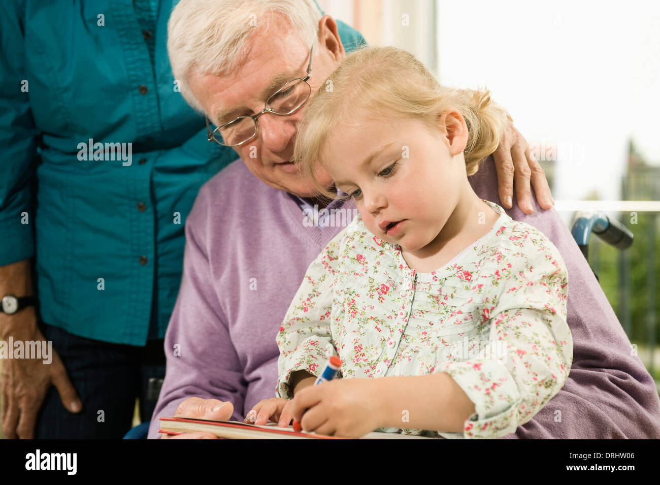 Nonno e nipote disegnare insieme, nonna in background, Baviera, Germania Foto Stock