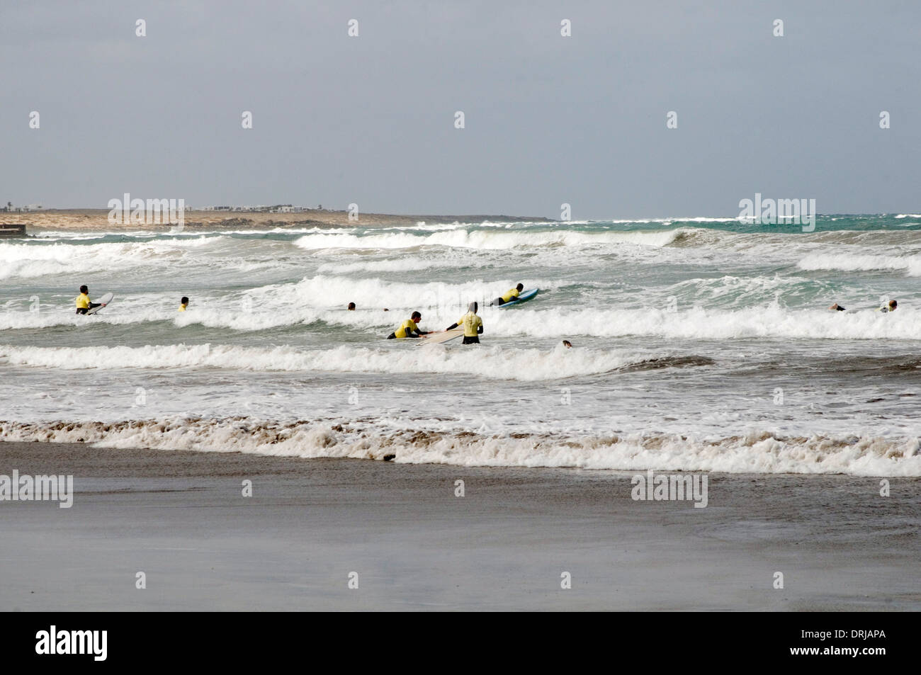 Surfers tavole da surf surf beach onde mare voce al surf fino muta muta muta adatta a spiaggia sabbiosa Playa famara lanz Foto Stock