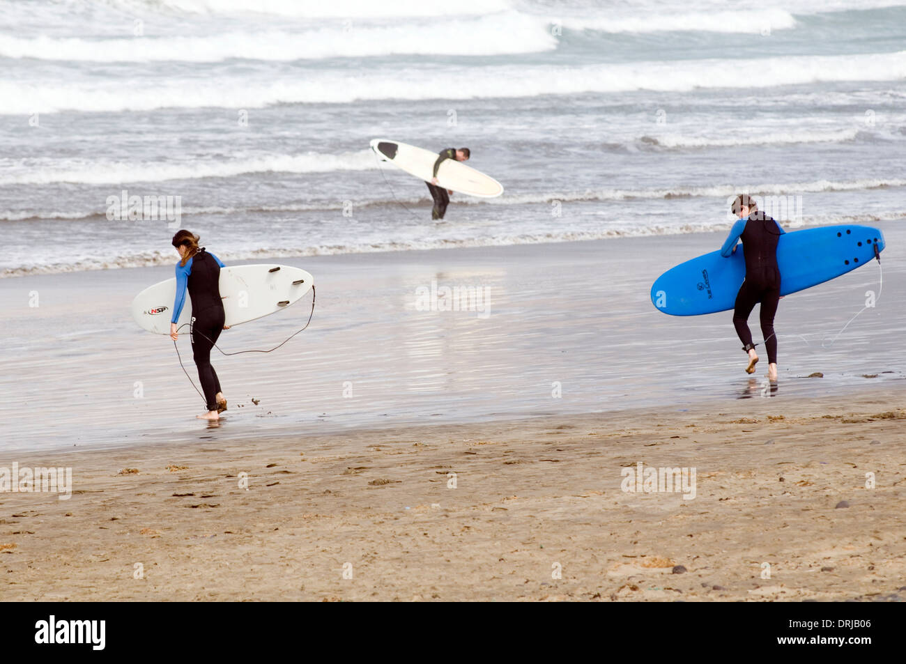 Surfers che trasportano le tavole da surf surf beach onde mare voce al surf fino muta muta muta adatta a spiaggia sabbiosa Playa fam Foto Stock