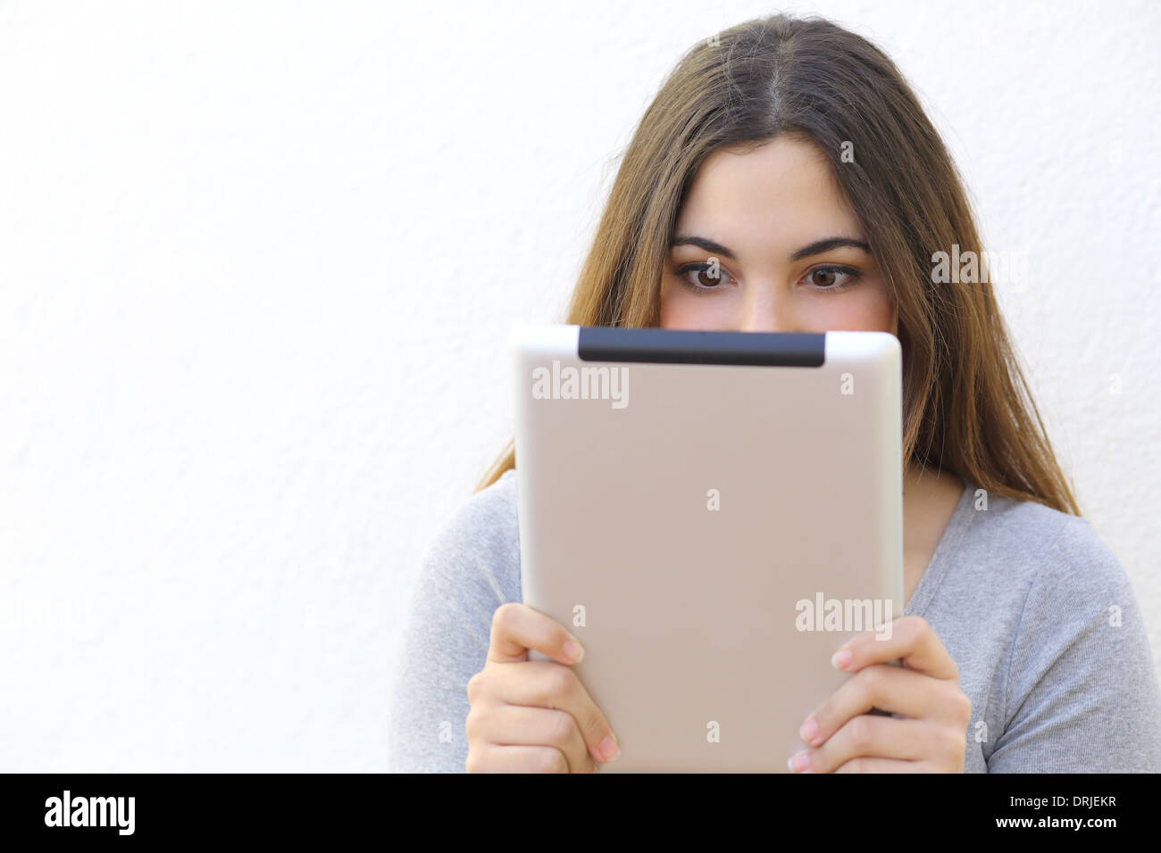 La dipendenza da Internet donna di lettura di un lettore di tablet PC su un muro bianco sullo sfondo Foto Stock