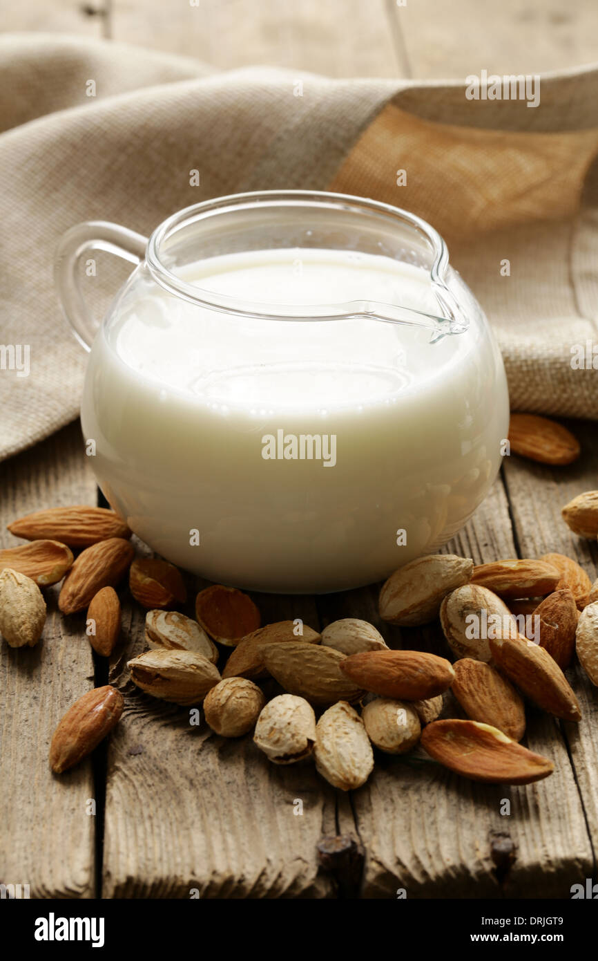 Latte di Mandorla in una caraffa di vetro con frutti a guscio interi Foto Stock