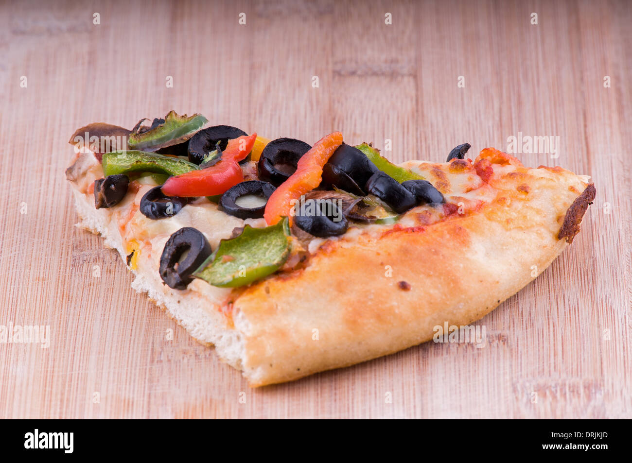 Pizza vegetariana pezzo su un tagliere, topping includono Olive Pomodori, pepe e formaggio Foto Stock
