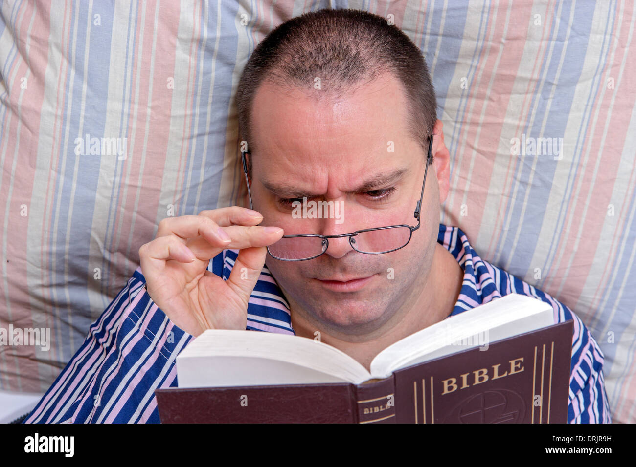 L'uomo della lettura della Bibbia nel letto Foto Stock