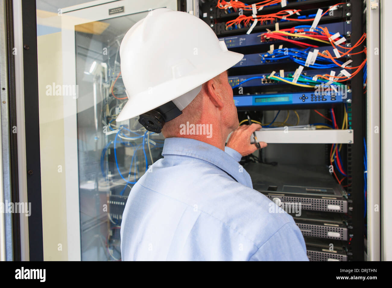 Ingegnere di impianto di potenza elettrico in sala di controllo guardando al server e switch Foto Stock