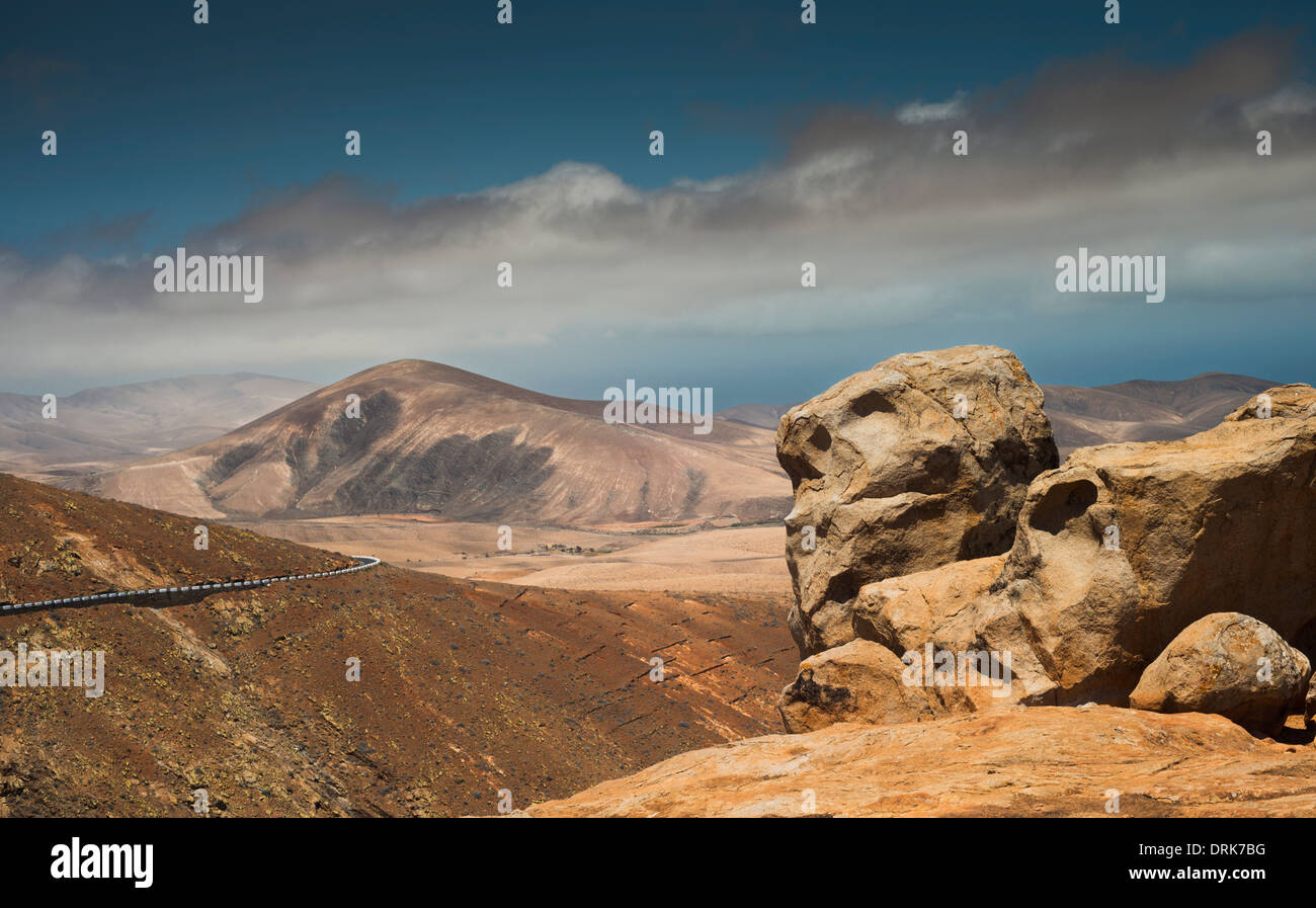 Weathered sienite rock, con gabbri e pyroxenite montagne sullo sfondo, parte dell'invadente complesso basale di Fuerteventura Foto Stock