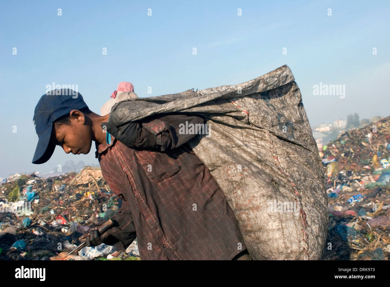 Un bambino operaio ragazzo sta portando un grande sacco pieno di spazzatura al tossico Stung Meanchey discarica in Phnom Penh Cambogia. Foto Stock