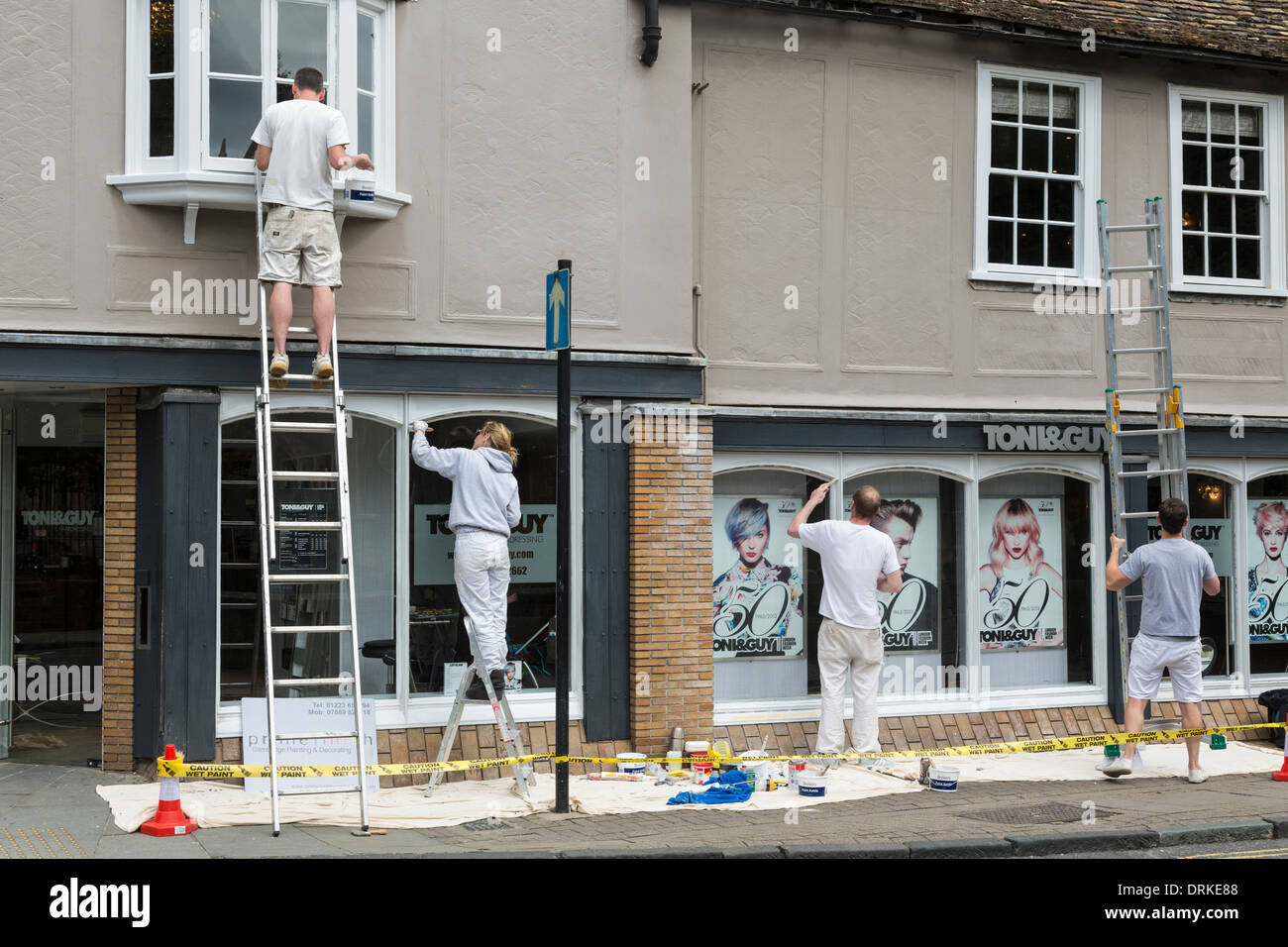 Team di pittori, uno su scale, Paint Shop Front, Cambridge, Inghilterra Foto Stock