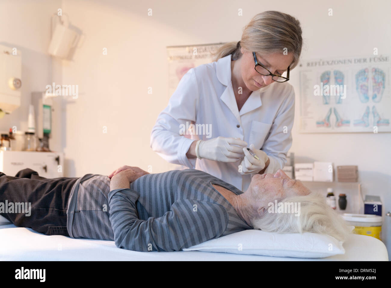 Femmina medico alternativo dando senior donna agopuntura iniezione Foto Stock