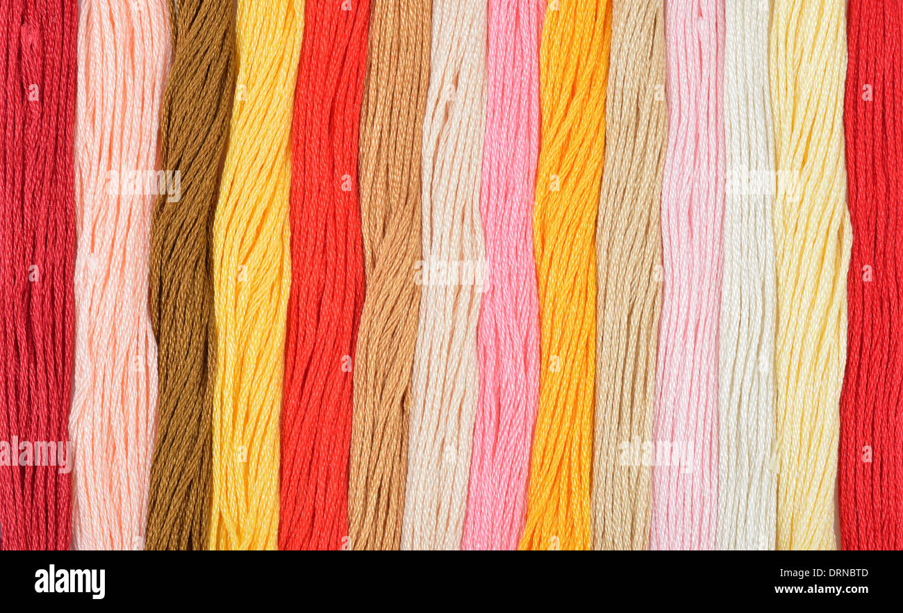 Colorati fili di ricamo in una fila. Colori caldi dello sfondo. Foto Stock