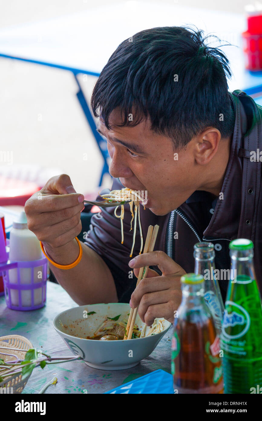 Uomo tailandese per mangiare in una bancarella di strada a Bangkok, in Thailandia Foto Stock