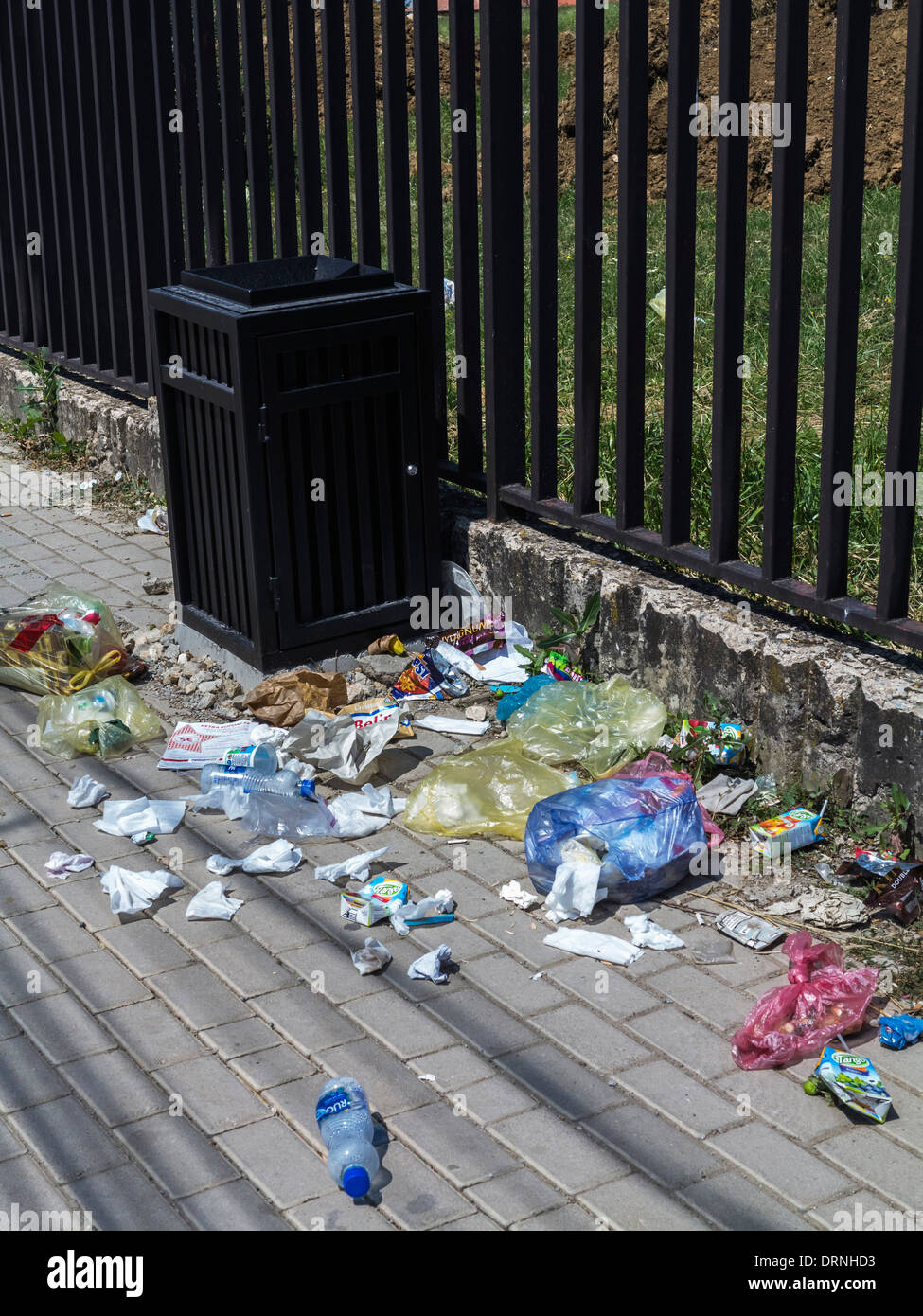 La spazzatura in strada accanto ad un vuoto nel cestino Foto Stock