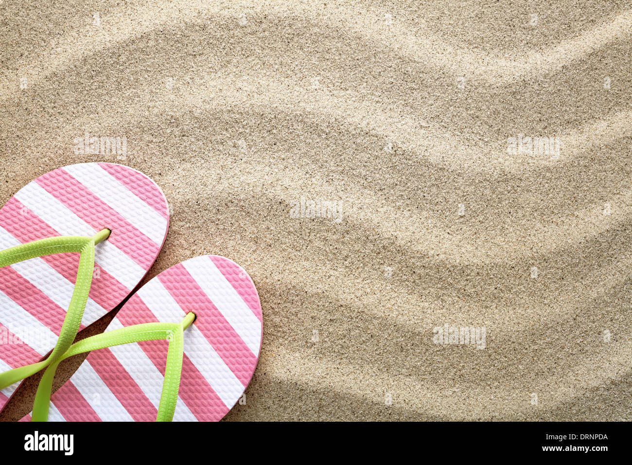 Spiaggia di sabbia con uno sfondo con flip flop. Concetto di estate. Vista superiore Foto Stock