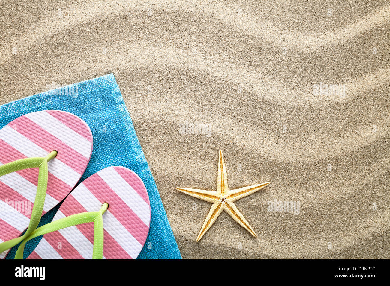Sfondo sabbia con asciugamano, ciabatte e stelle marine. Concetto di estate. Vista superiore Foto Stock