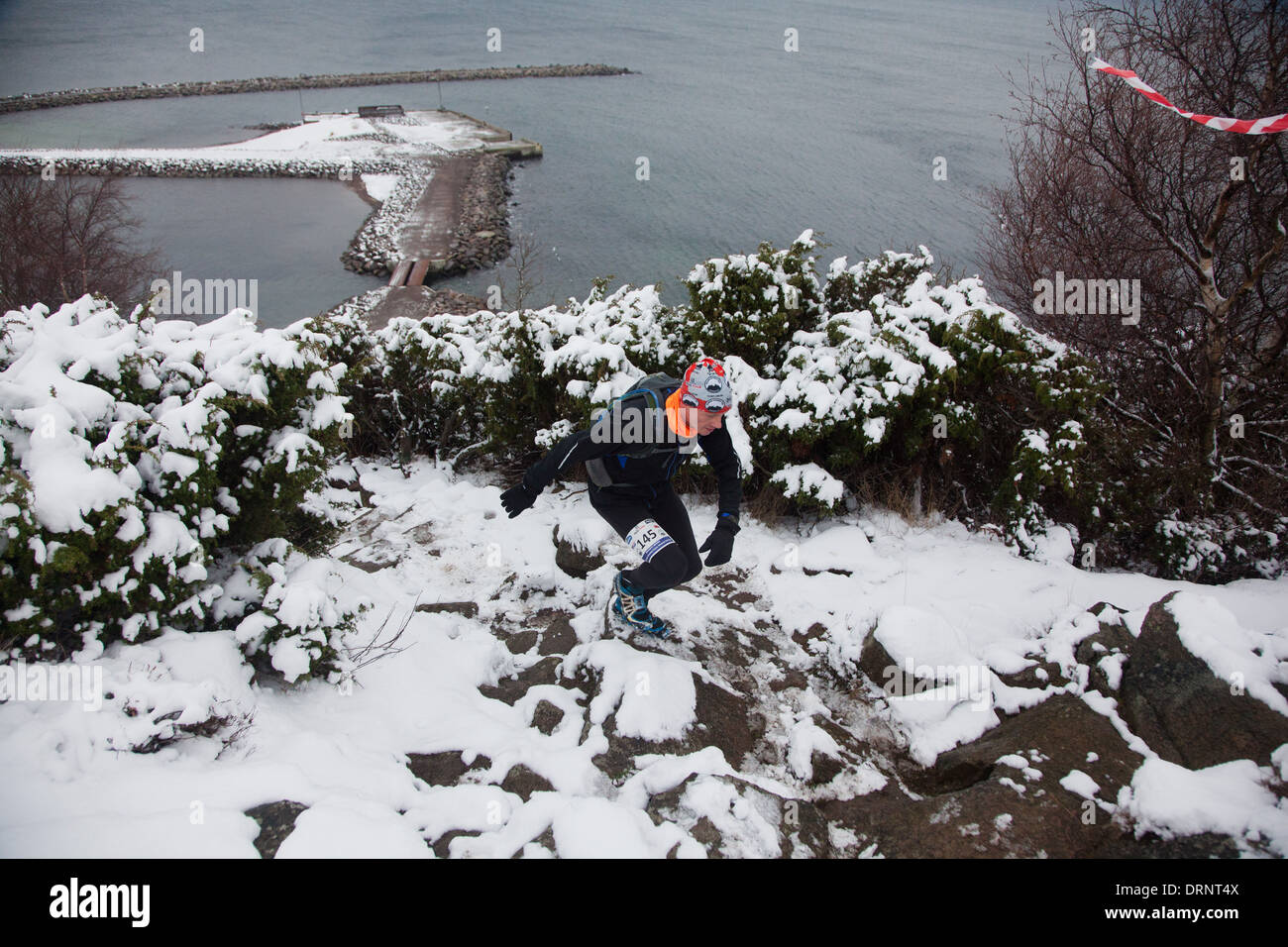 Un runner fa il suo modo fino a terreni innevati e percorso roccioso dal litorale di seguito. Foto Stock