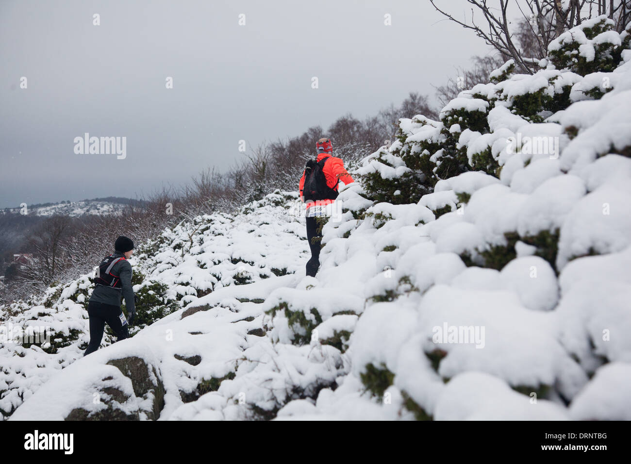 Runner facciano la loro strada fino a snowy percorso roccioso dalla linea di costa del nord Bornholm. Foto Stock