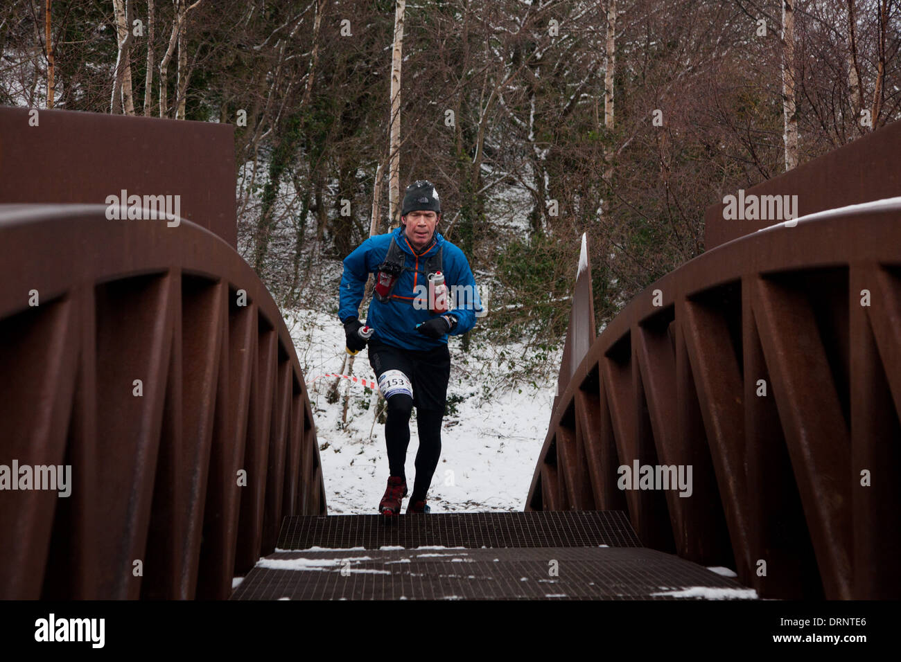 Un maratoneta attraversa un piccolo ponte di metallo come parte del sentiero e corrono lungo il litorale di Bornholm. Foto Stock