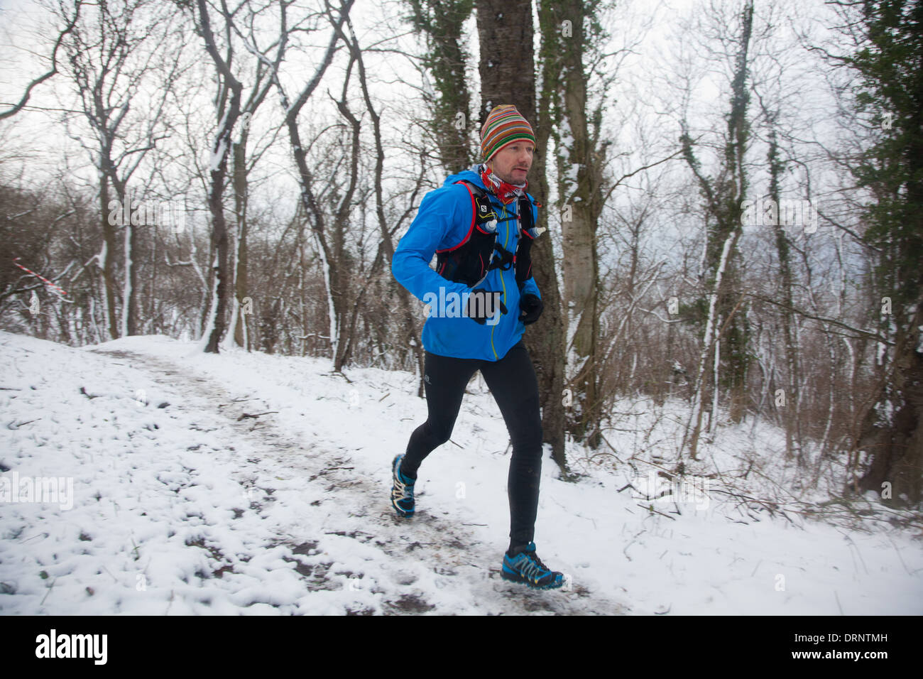 Un runner fa la sua strada giù per un sentiero innevato attraverso il bosco in prossimità di Hammershus. Foto Stock