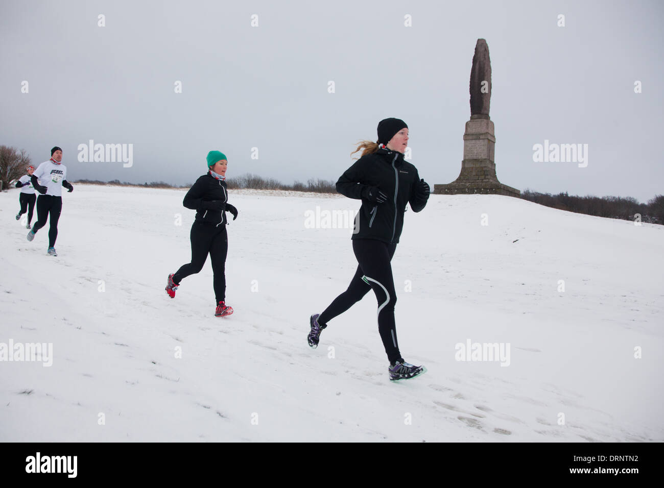 Runner facciano la loro strada attraverso la neve oltre le rovine di Hammershus entrata di pietra. Foto Stock