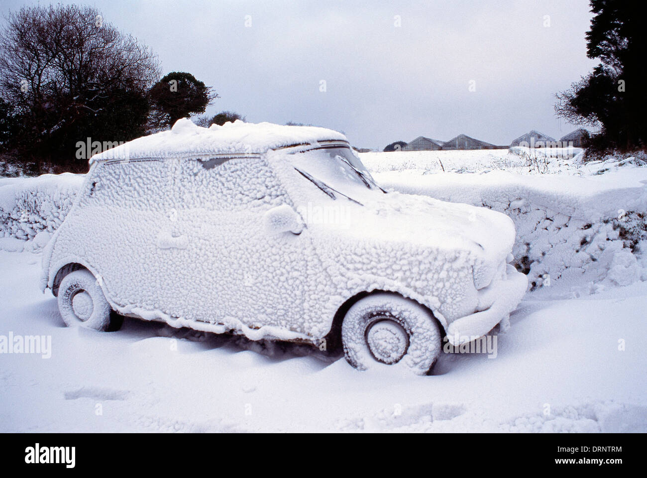 Guernsey. Scena invernale con mini auto bloccata in snow drift. Foto Stock
