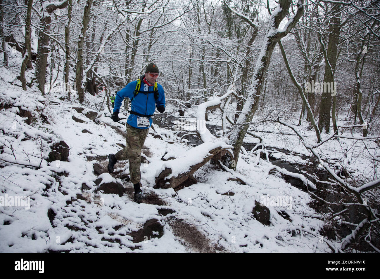 Un runner fa il suo modo attraverso i bit di bosco lungo un sentiero stretto. Foto Stock