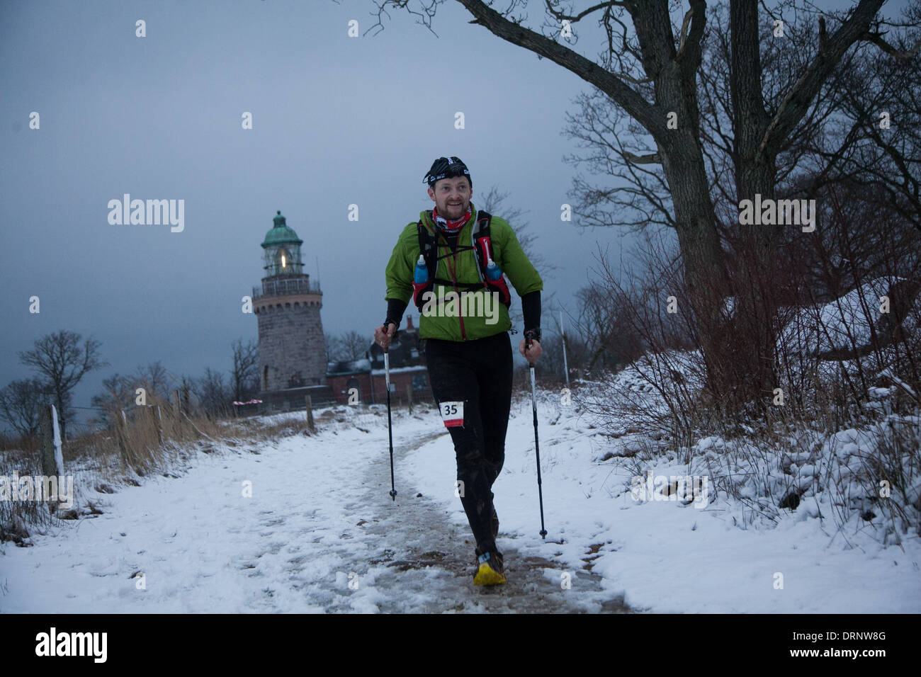 Un runner fa il suo modo di morire luce uscente martello Knude Light house dietro. Foto Stock