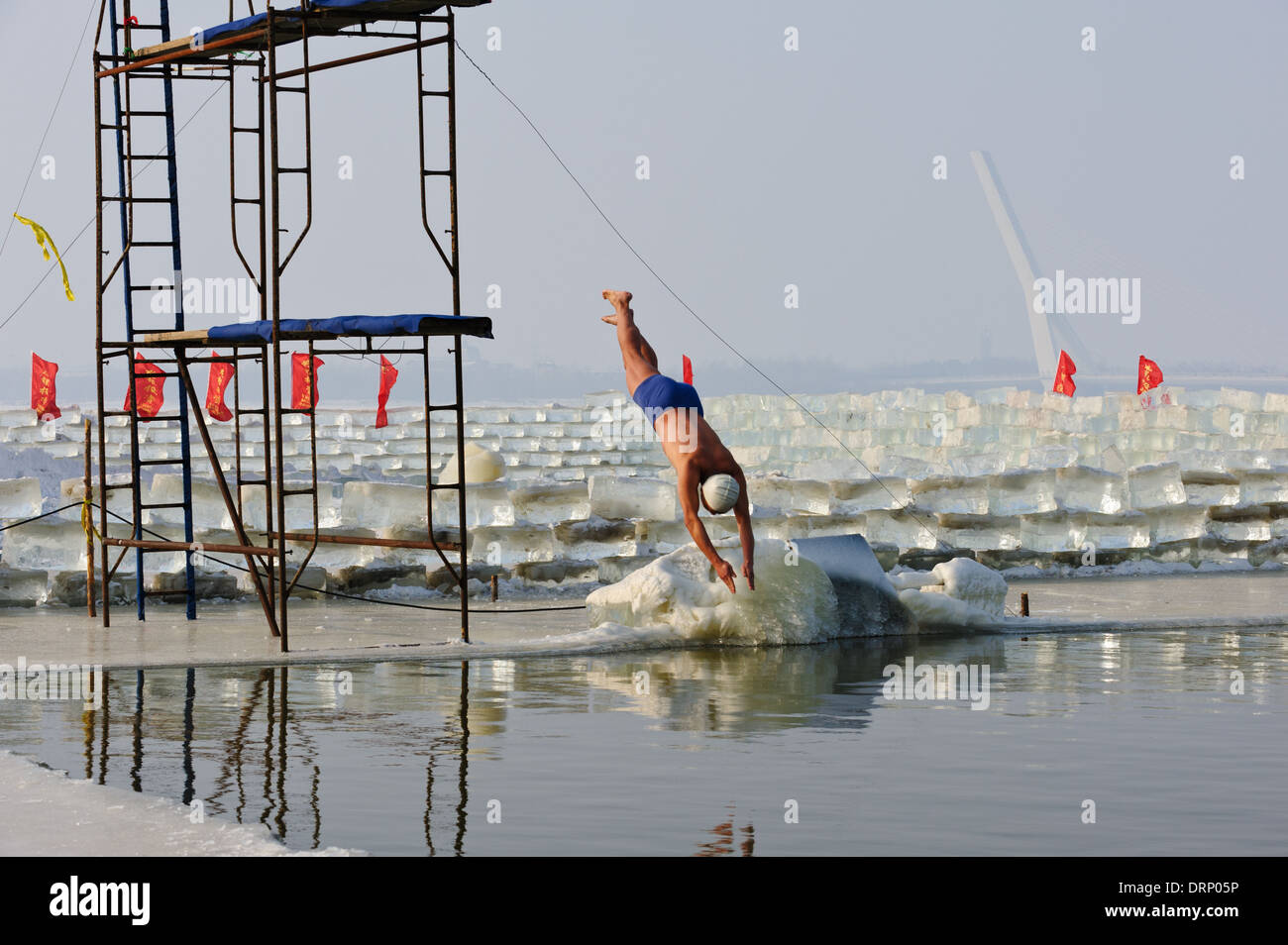 Nuotatore di ghiaccio si tuffa nell'acqua fredda del fiume Songhua, Harbin, Cina. Un buco nel ghiaccio viene mantenuta aperta per il nuoto. Foto Stock