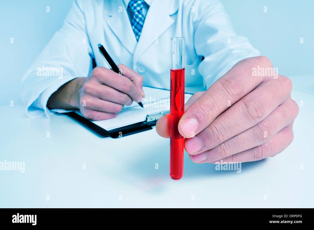 Un uomo che indossa mantello bianco tenendo un campione di sangue in sua mano Foto Stock