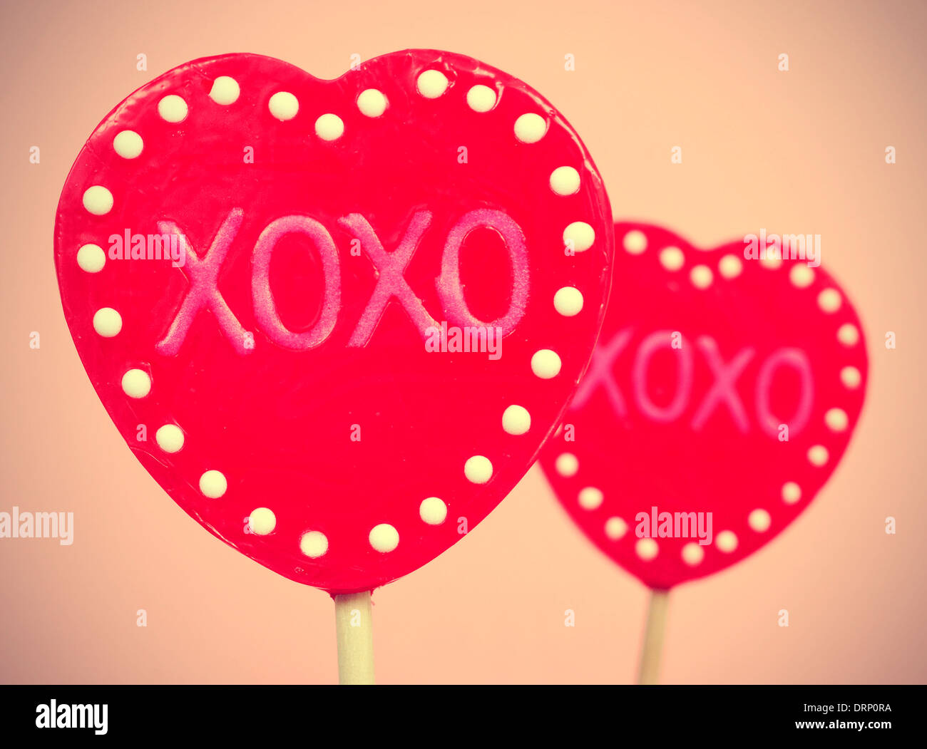 Foto di alcuni a forma di cuore lecca lecca con il testo XOXO, baci e abbracci, scritto in essi, con un effetto retrò Foto Stock
