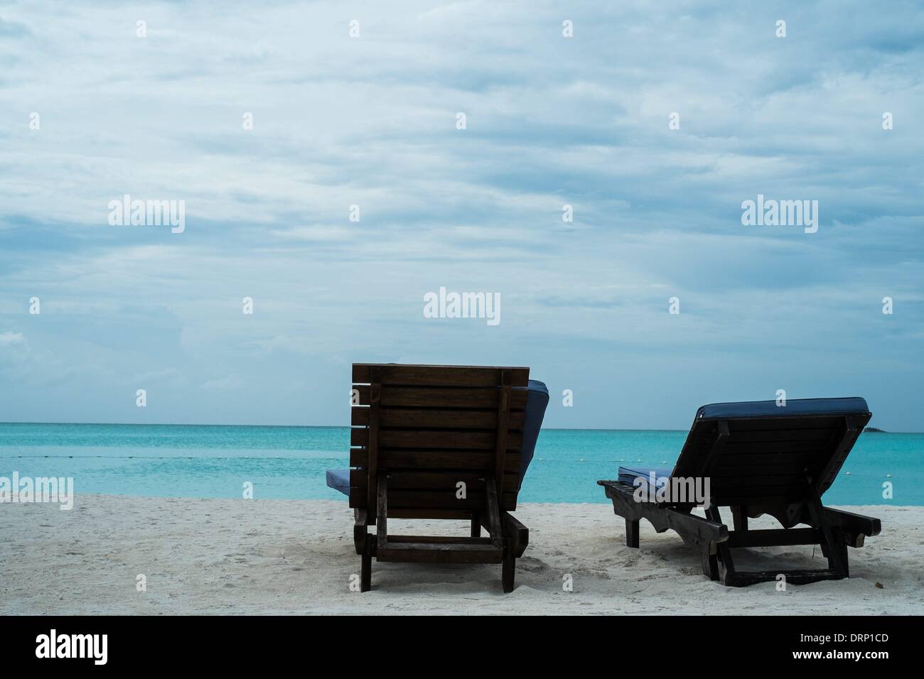 Sedie a sdraio sulla spiaggia sull'isola caraibica di antigua sotto una copertura nuvolosa. - Ottobre 2013. Foto Stock