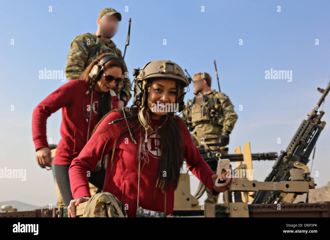 Washington Redskins football team cheerleader sorride dopo la cottura di un M240B mitragliatrice durante una visita alla US Army delle forze speciali militari 24 gennaio 2014 vicino a Kabul, Afghanistan. Porzioni di immagine sono stati sfumata per motivi di sicurezza da parte dei militari. Foto Stock